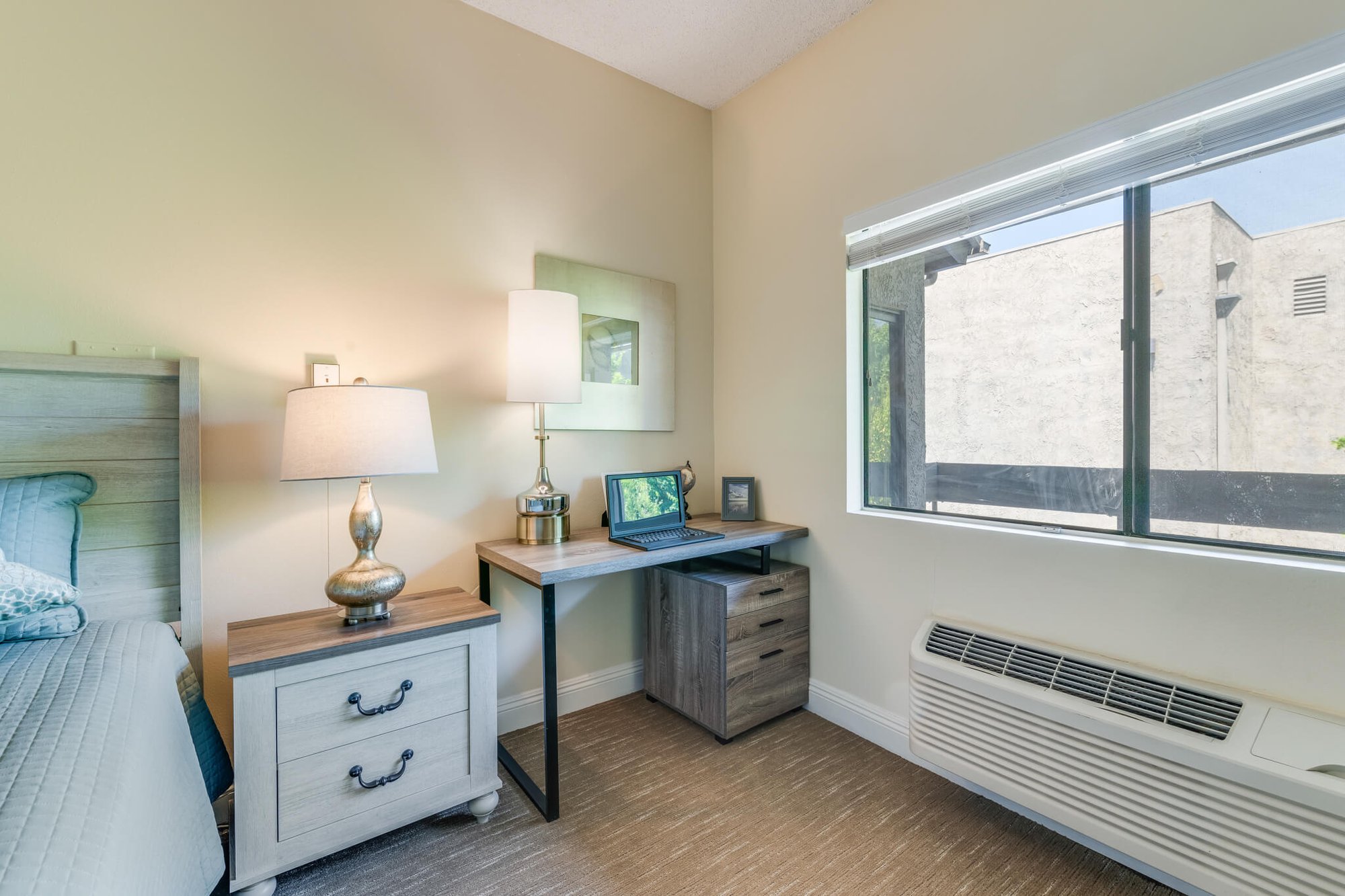 Bright, furnished resident room with a desk and lamp.