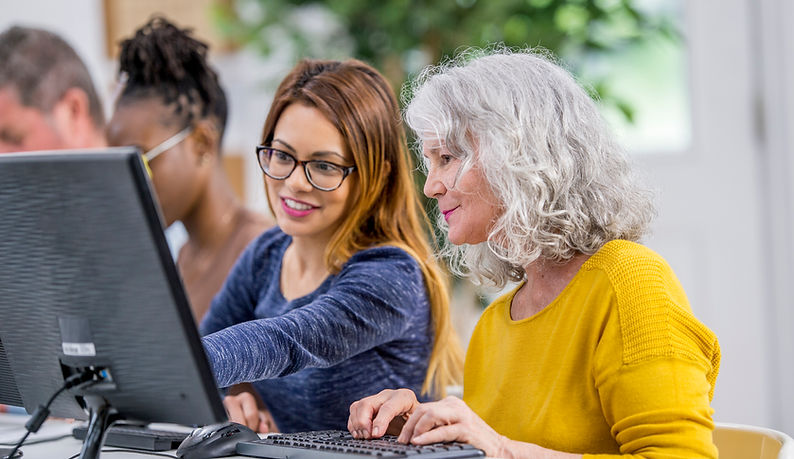 Residents engaging in computer activities with staff assistance.