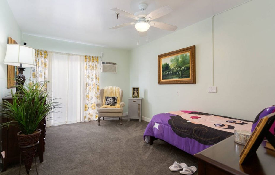 A cozy resident bedroom with a bed and chair.