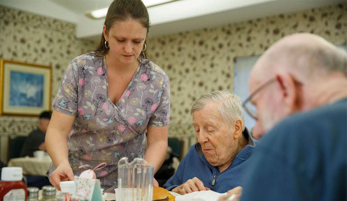 Staff serving a meal to residents in the dining room.