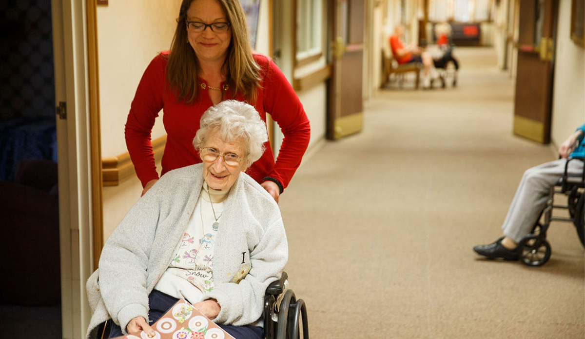 Caregiver assisting a resident in a hallway