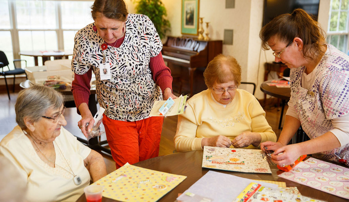 Residents engaging in a crafting activity with staff assistance.