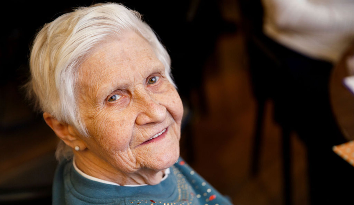 Smiling elderly woman in a facility setting.