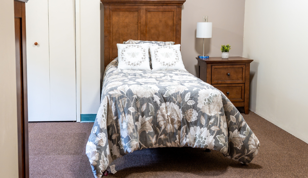 Cozy bedroom with floral bedding and bedside table.