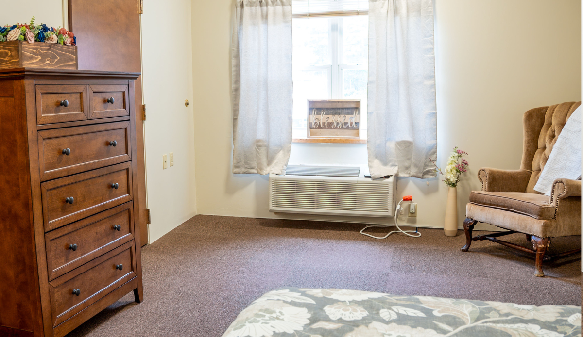Cozy resident room with a dresser and armchair
