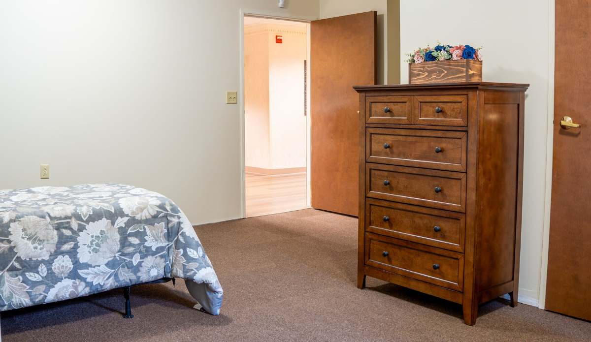 A spacious private room with a dresser and bed.