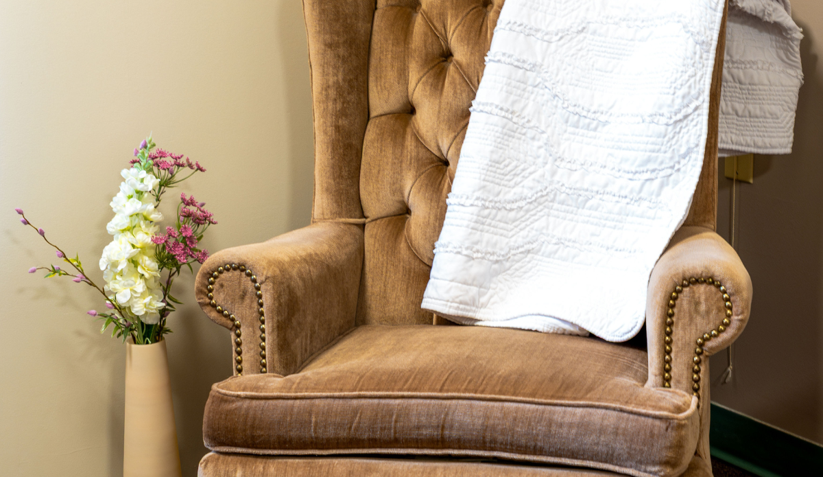 Cozy armchair with a blanket and flower vase.