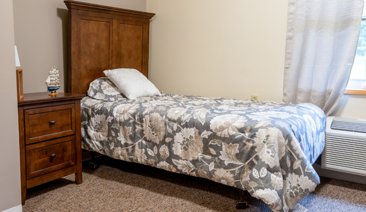 Cozy bedroom with floral bedding and a nightstand.
