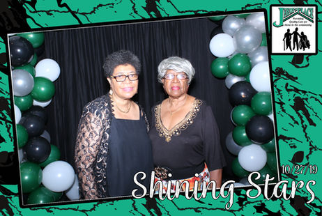 Two women posing at an event backdrop.