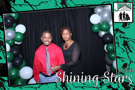 Two people posing at an event with balloons.