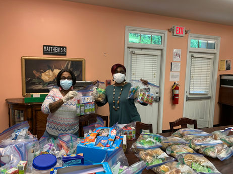 Two staff members with food packages in an indoor setting.