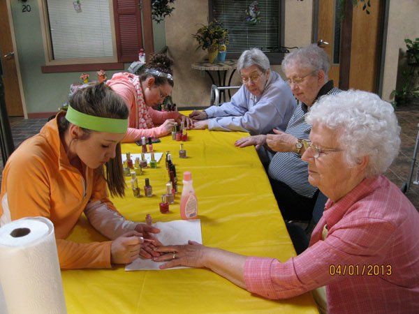 Residents enjoying nail painting activity with staff.