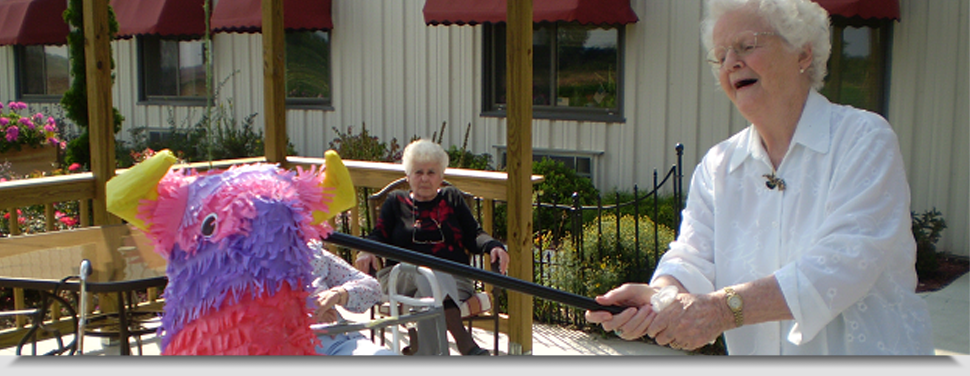 Senior woman hitting a colorful piñata outdoors.