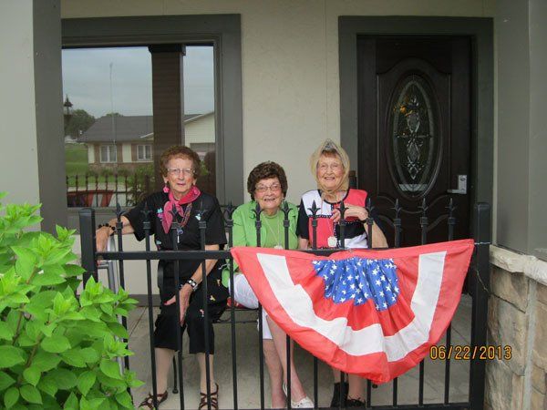 Three women celebrating outside a building with decorations.