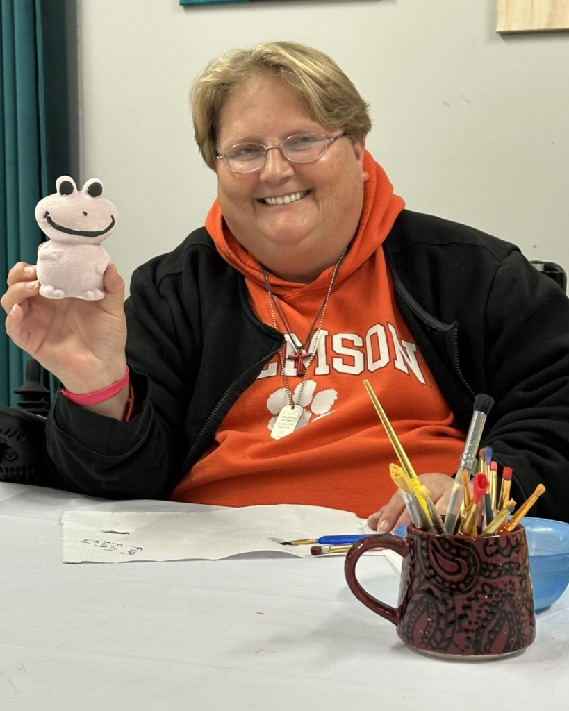 Woman showing a crafted frog figure.