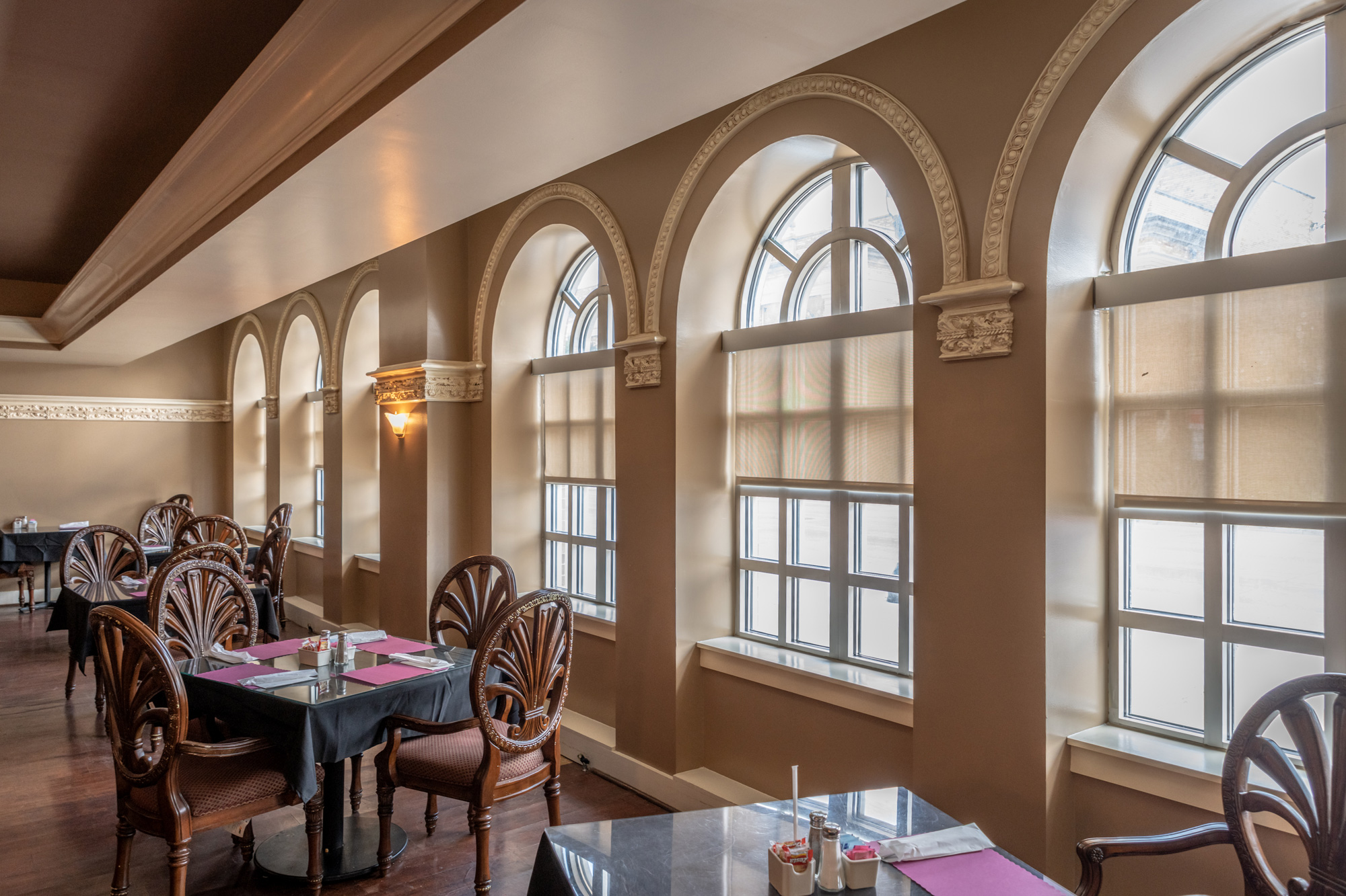 Elegant dining area with arched windows and tables.