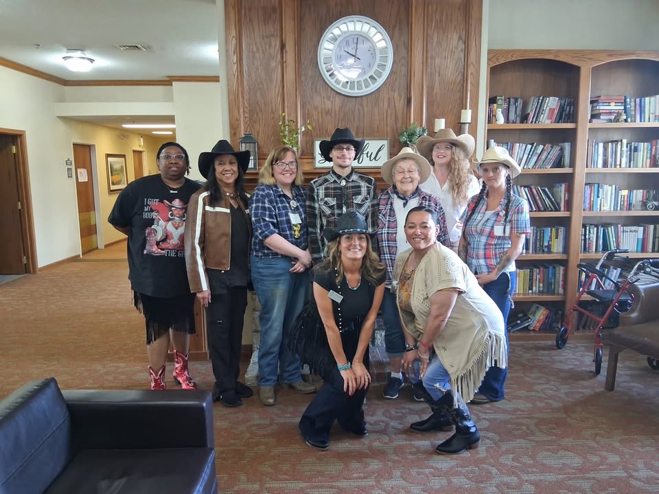 Staff and residents in cowboy-themed outfits in a common area.