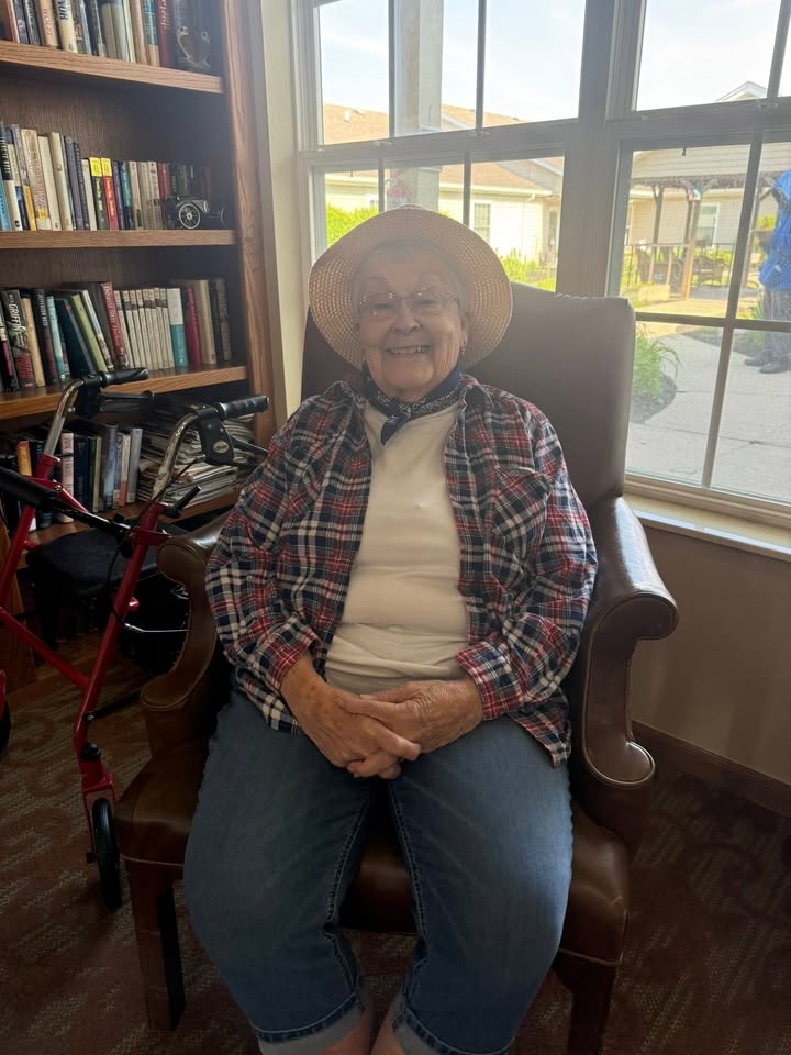 Resident sitting in a chair, surrounded by bookshelves.