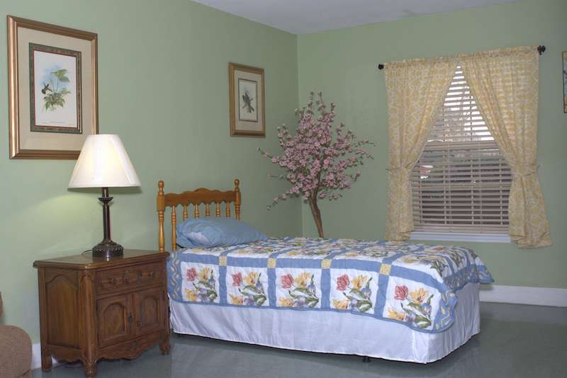 A cozy bedroom with a floral quilt and decorative elements.