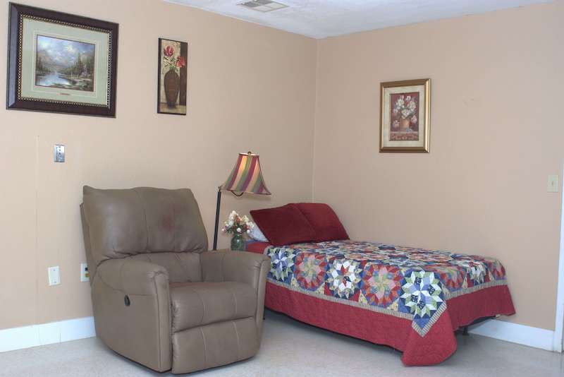 A cozy resident room with a bed and recliner.