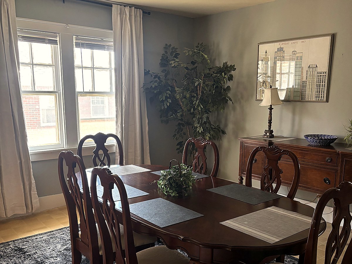 Well-furnished dining area with windows and plants.