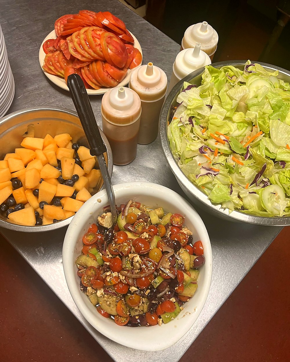 Variety of fresh salads and fruits in a dining setting.