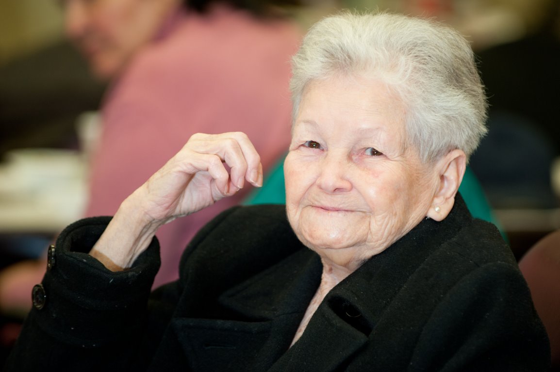 Elderly woman smiling in a social setting
