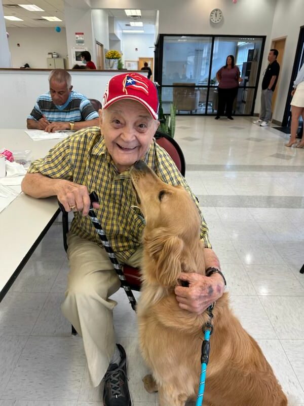 Elderly man with a dog in a community space.