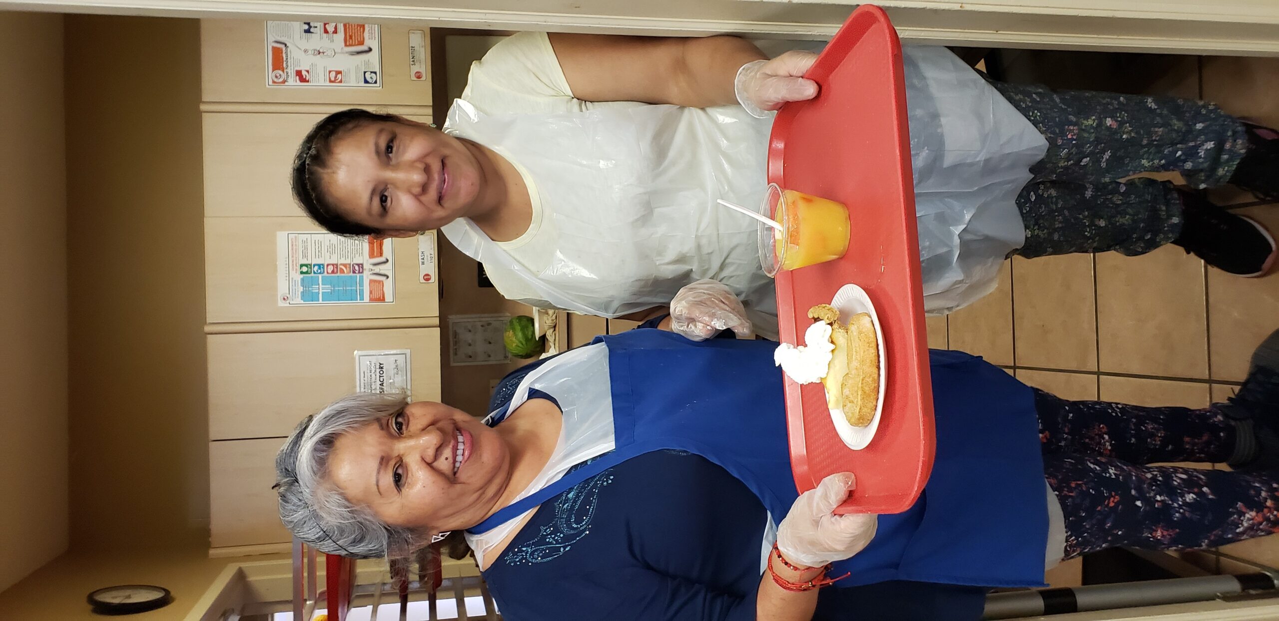 Staff and resident serving food in dining area.