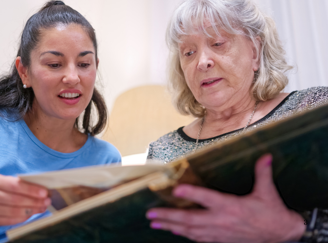 Staff member engaging with a resident over a photo book.