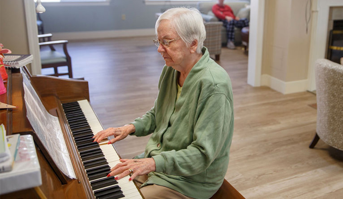Elderly woman playing piano in a common area