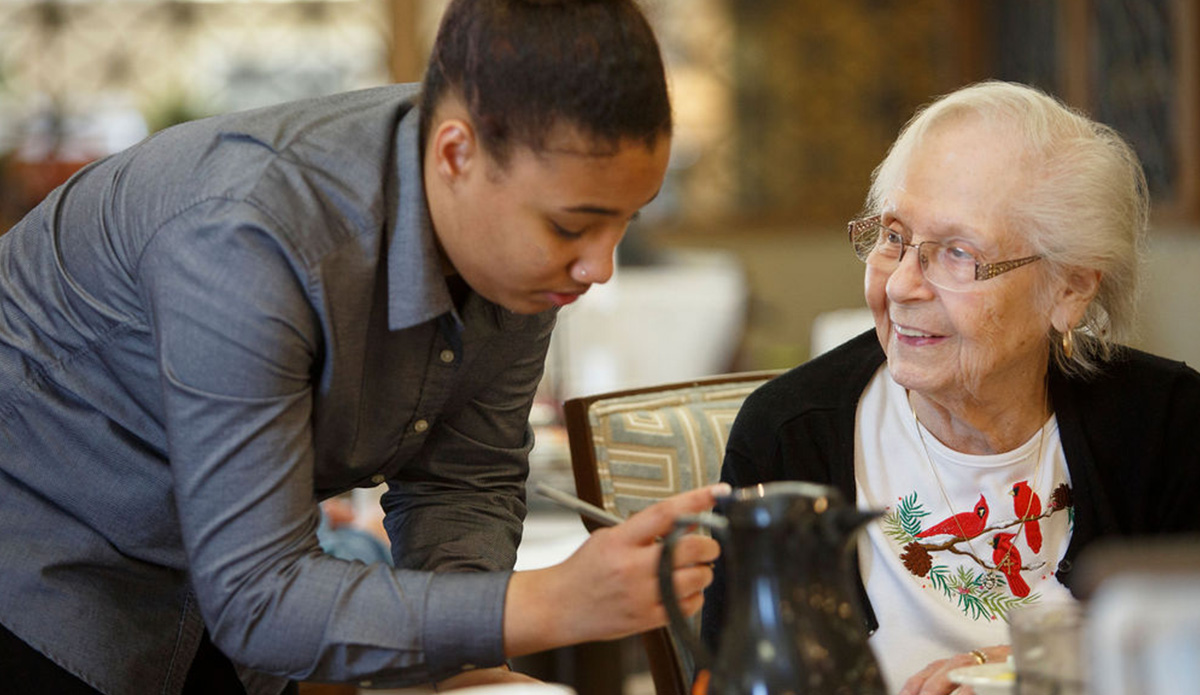 Staff assisting a resident in a dining area