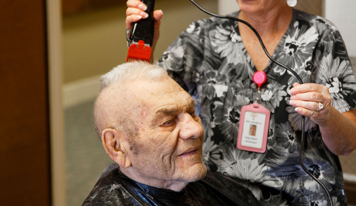 A senior receiving a haircut from staff.
