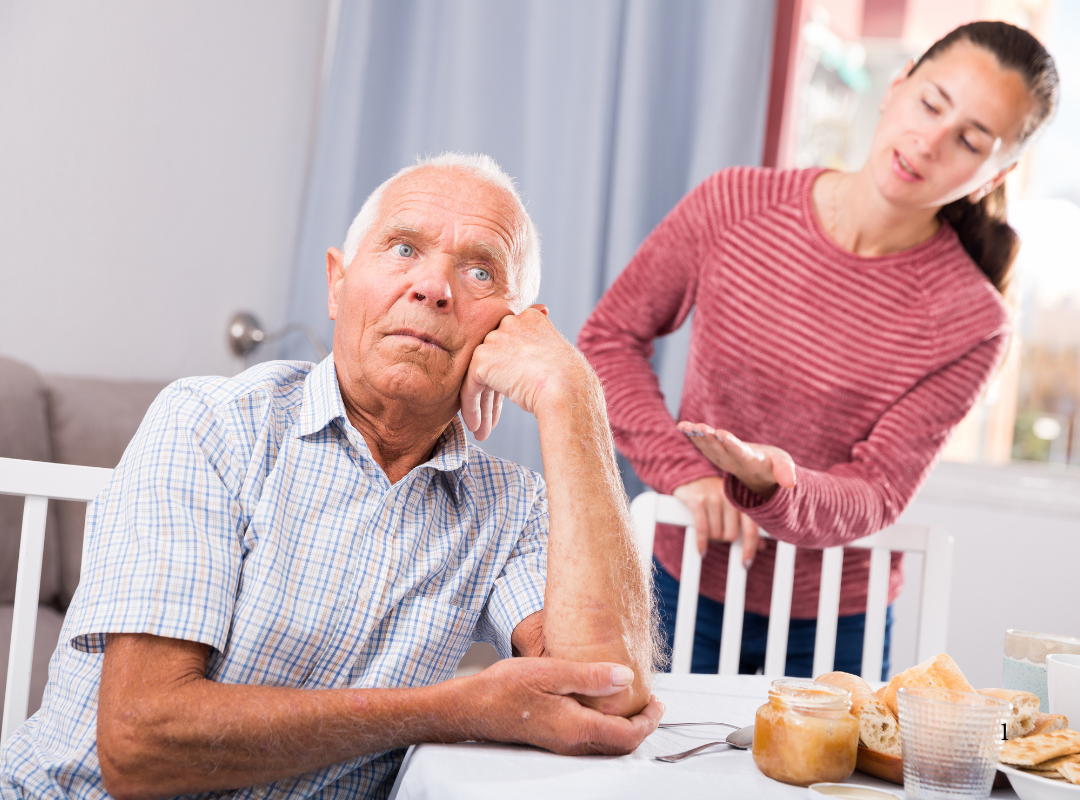 Elderly man at a table with caregiver