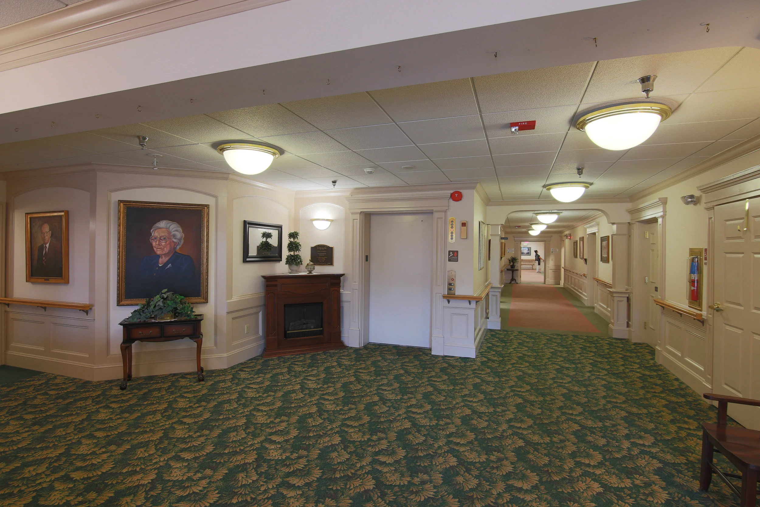 Interior view of a hallway with artwork and a fireplace.