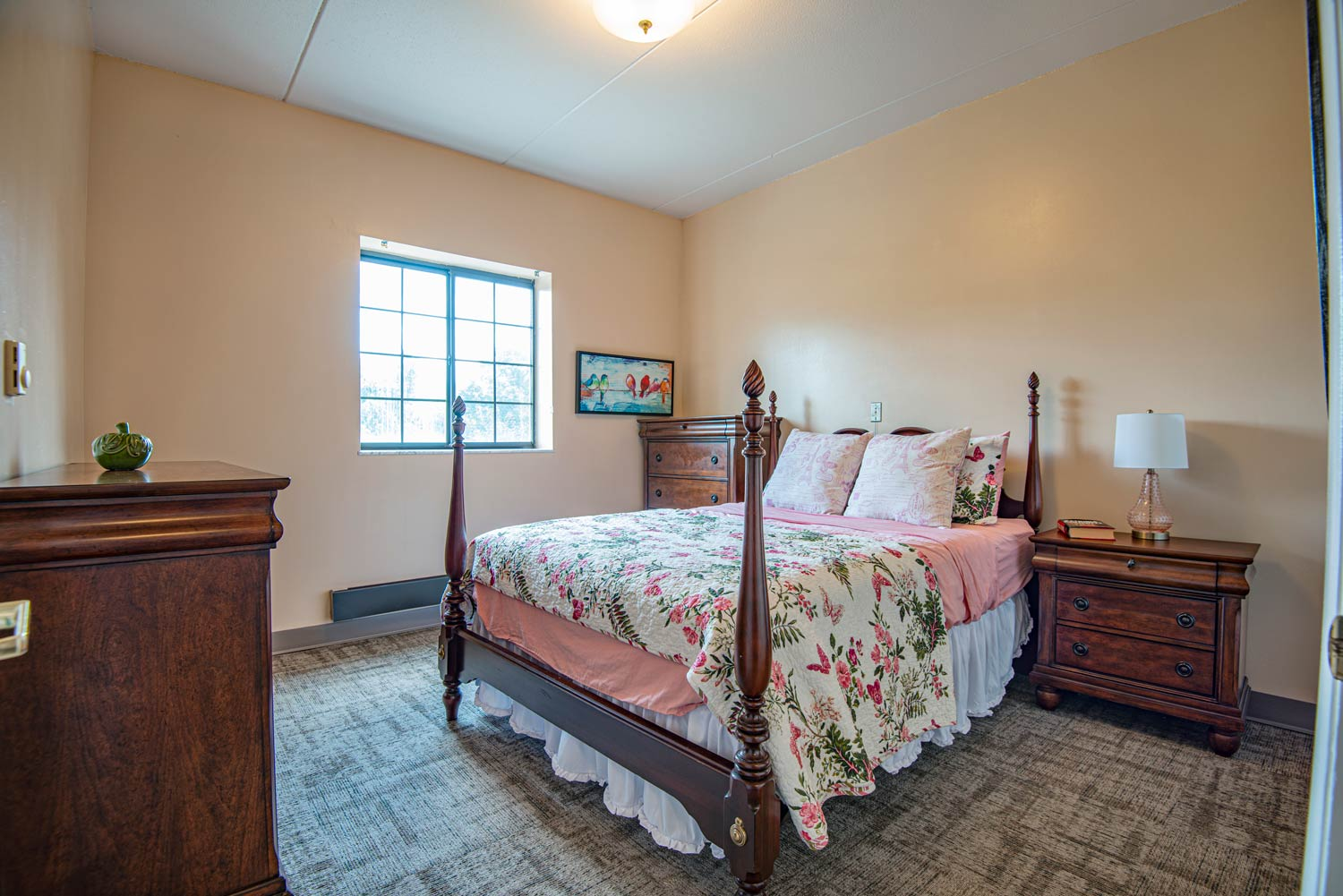 Cozy bedroom setup with floral bedding and furniture.