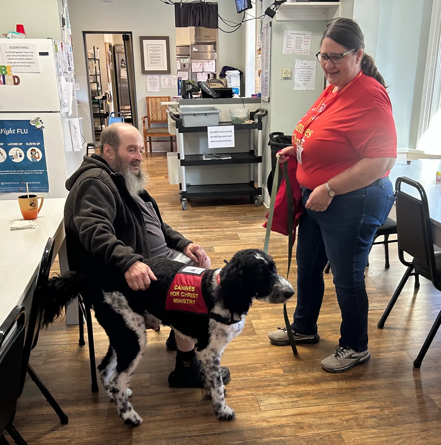 Resident interacting with staff and therapy dog.