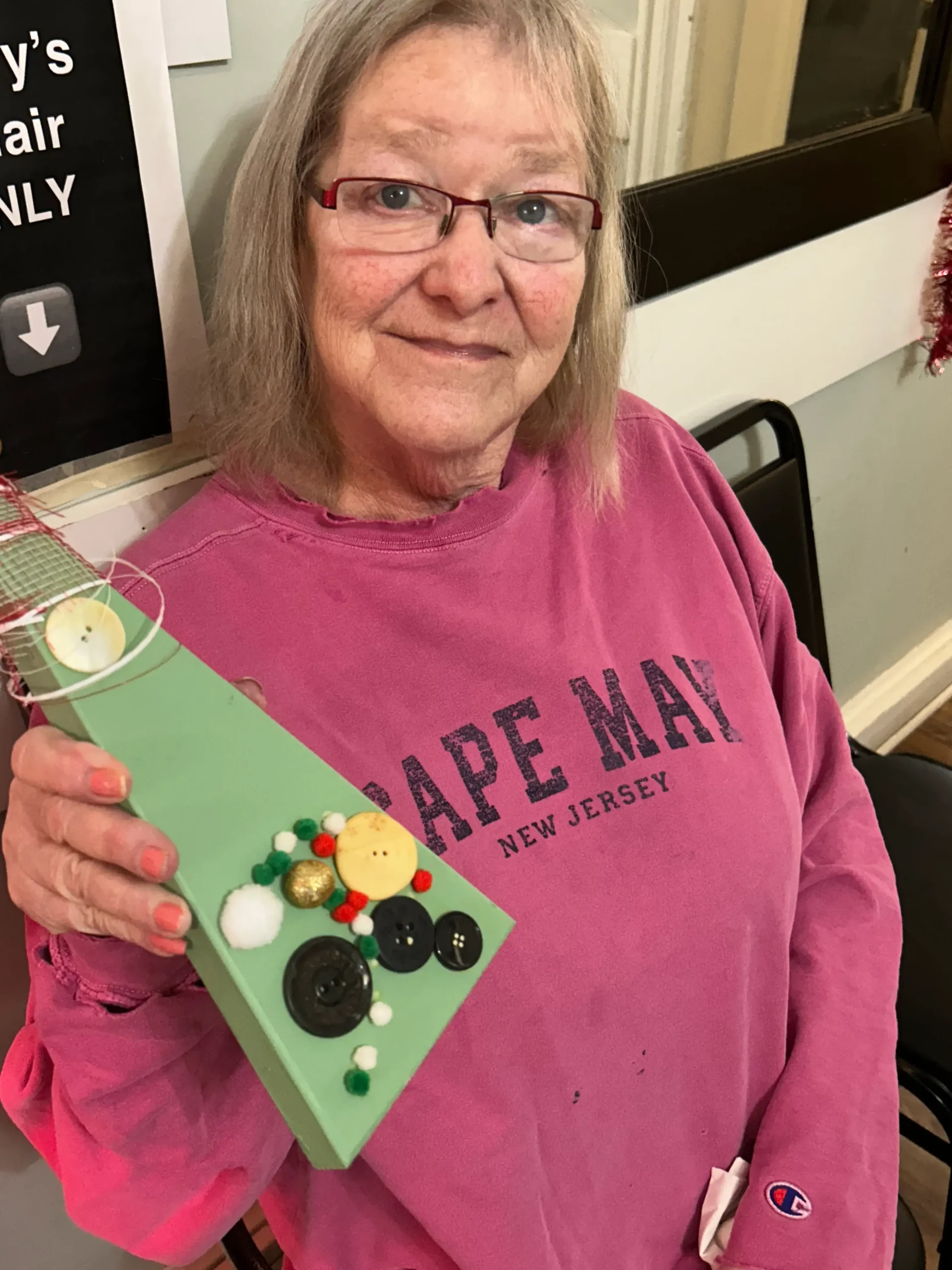 Resident joyfully holding a craft project.