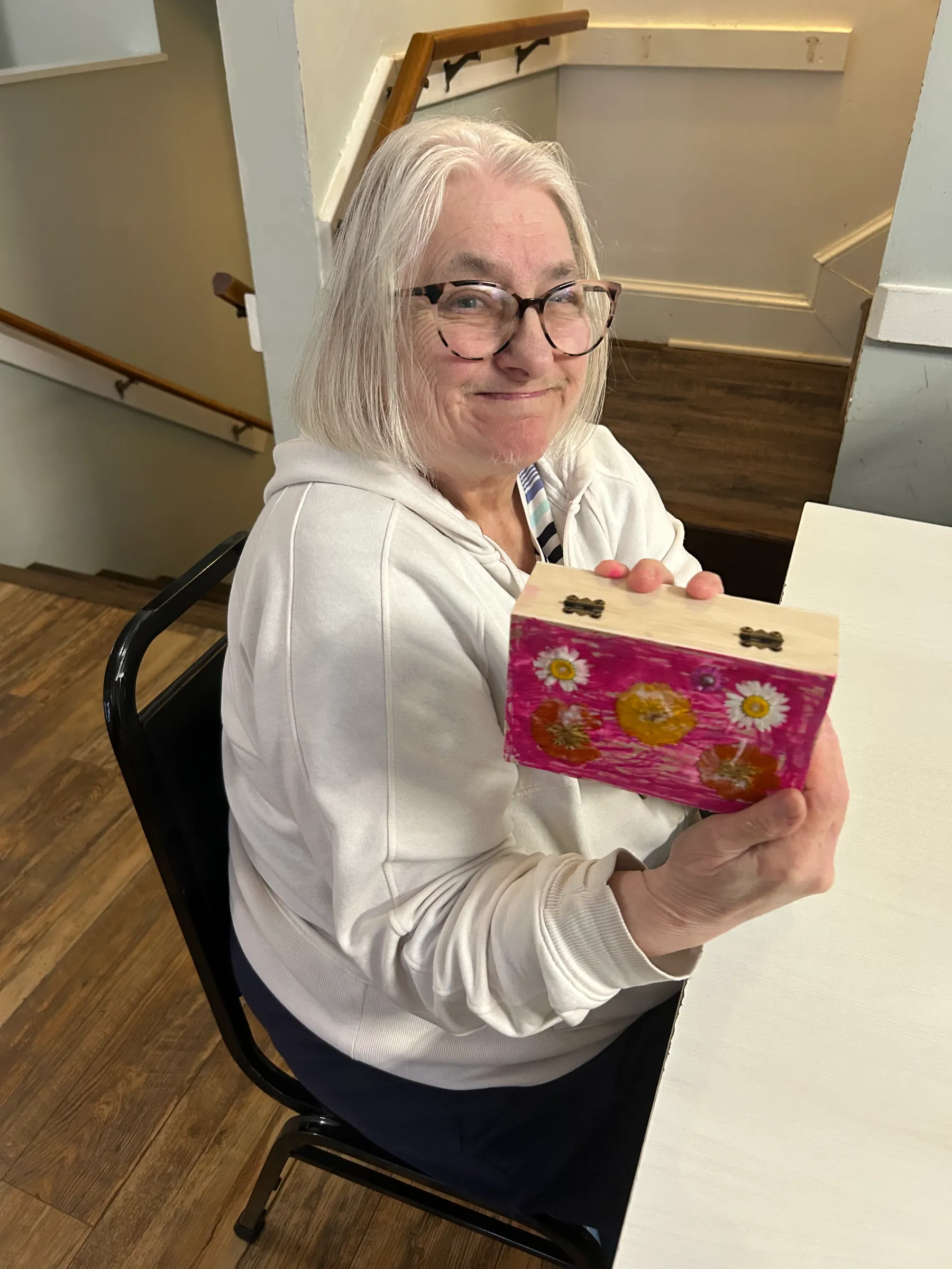 Resident smiling and holding a decorated box.