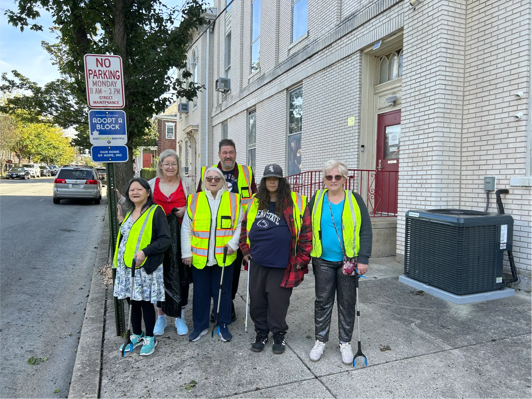 Residents and staff posing outside the facility in safety vests.