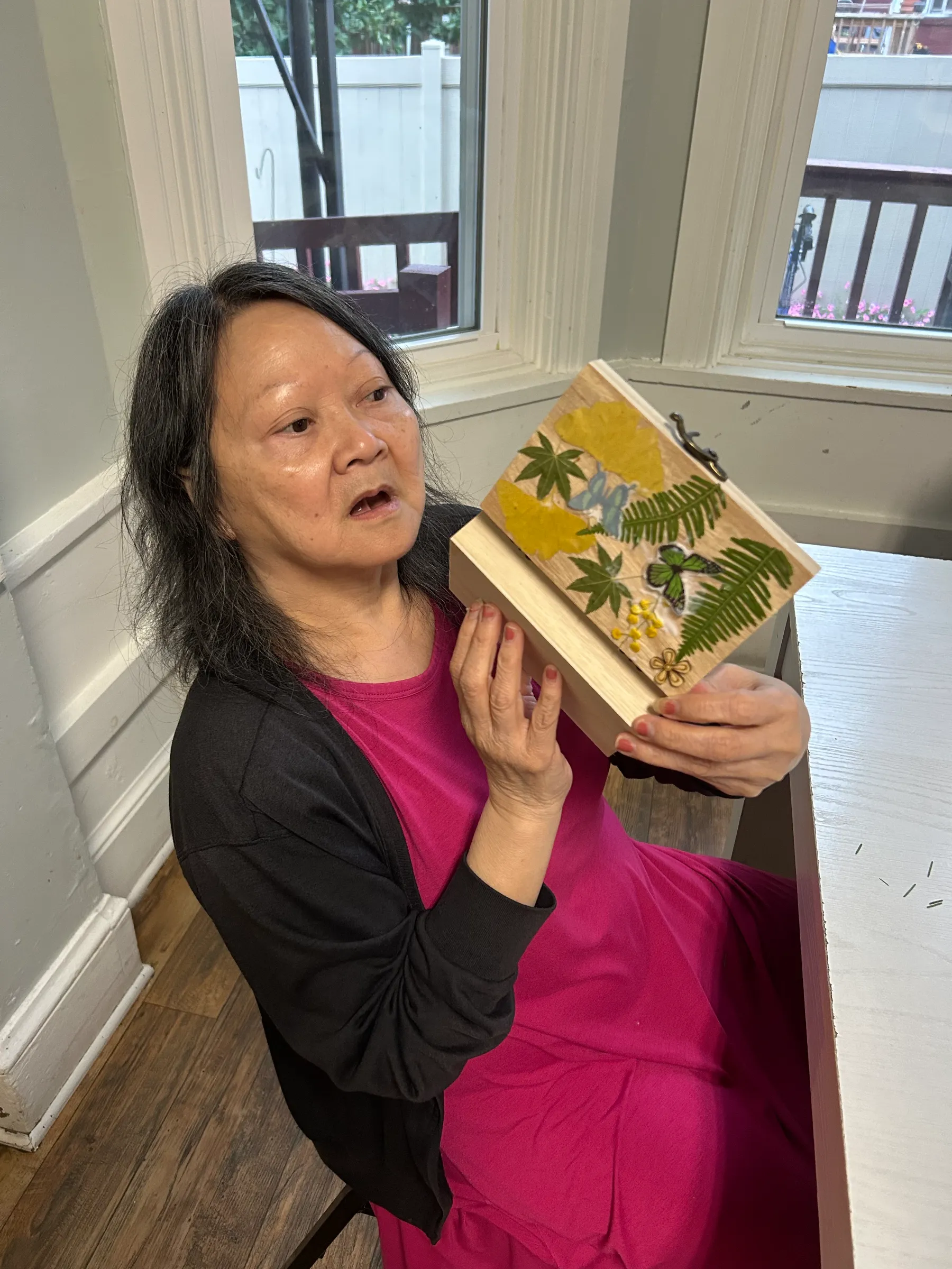 A resident showcasing a craft project indoors.