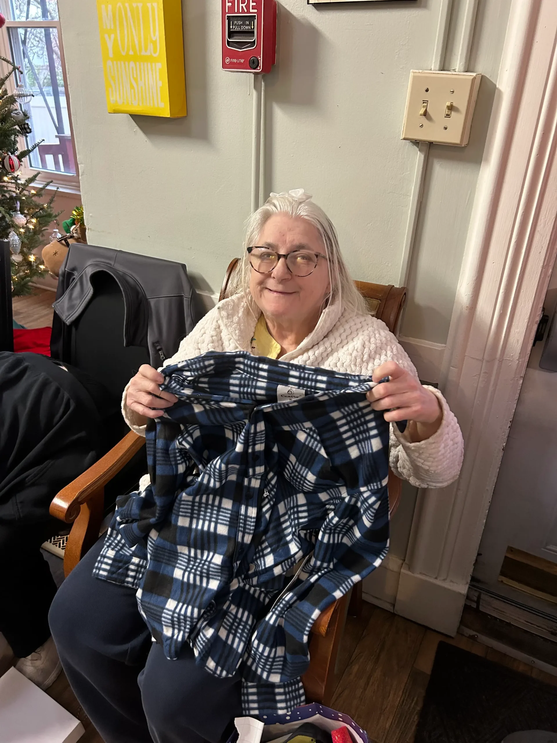 Resident holding a plaid garment in a cozy interior