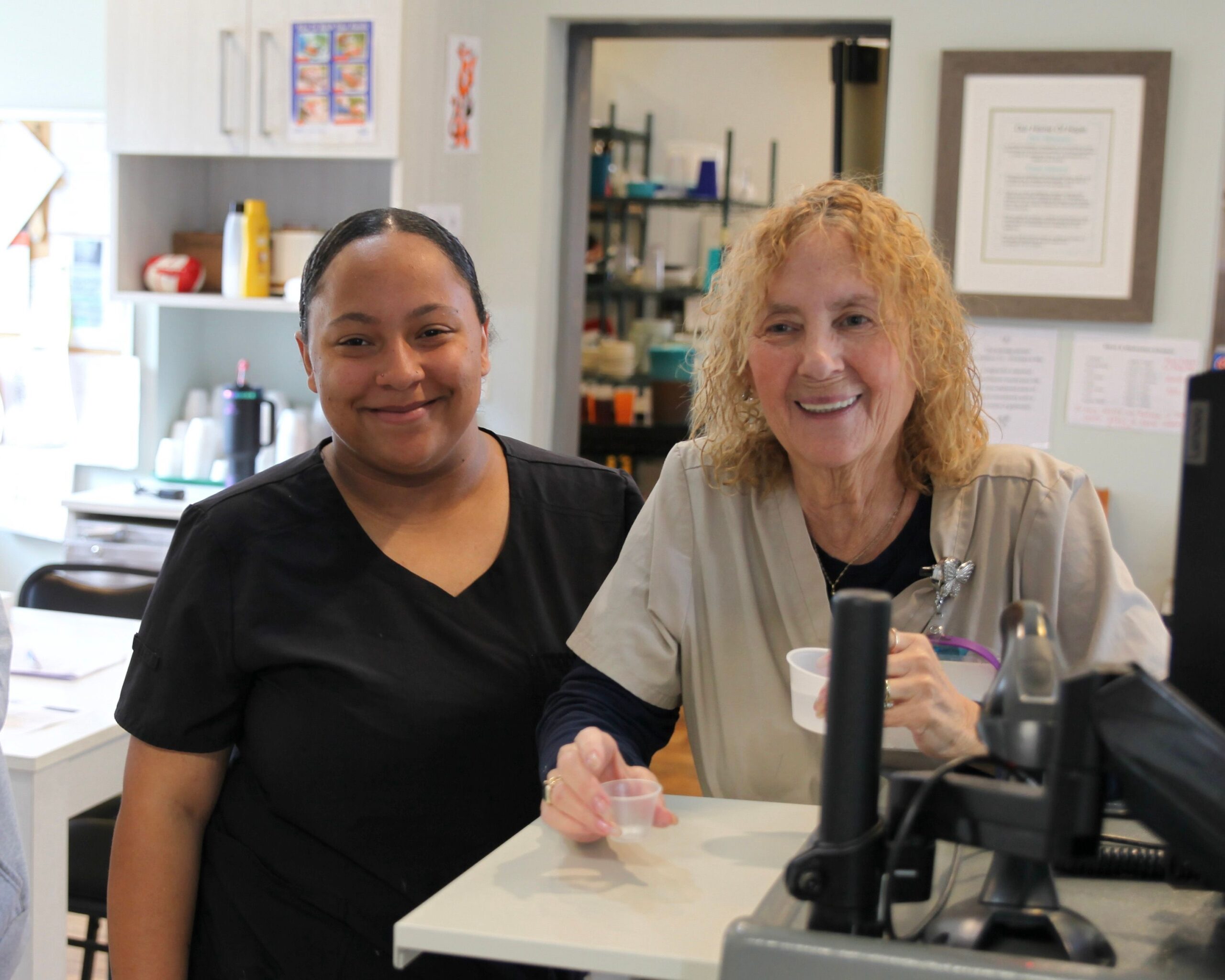 Two staff members smiling at a counter.