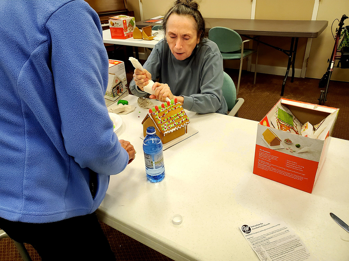 Resident decorating a gingerbread house.