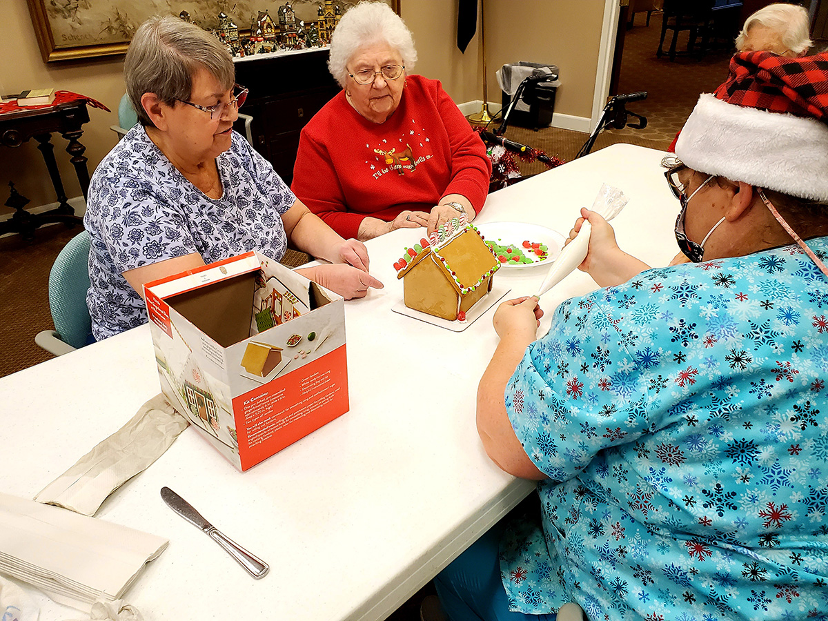 Residents decorating a gingerbread house together.