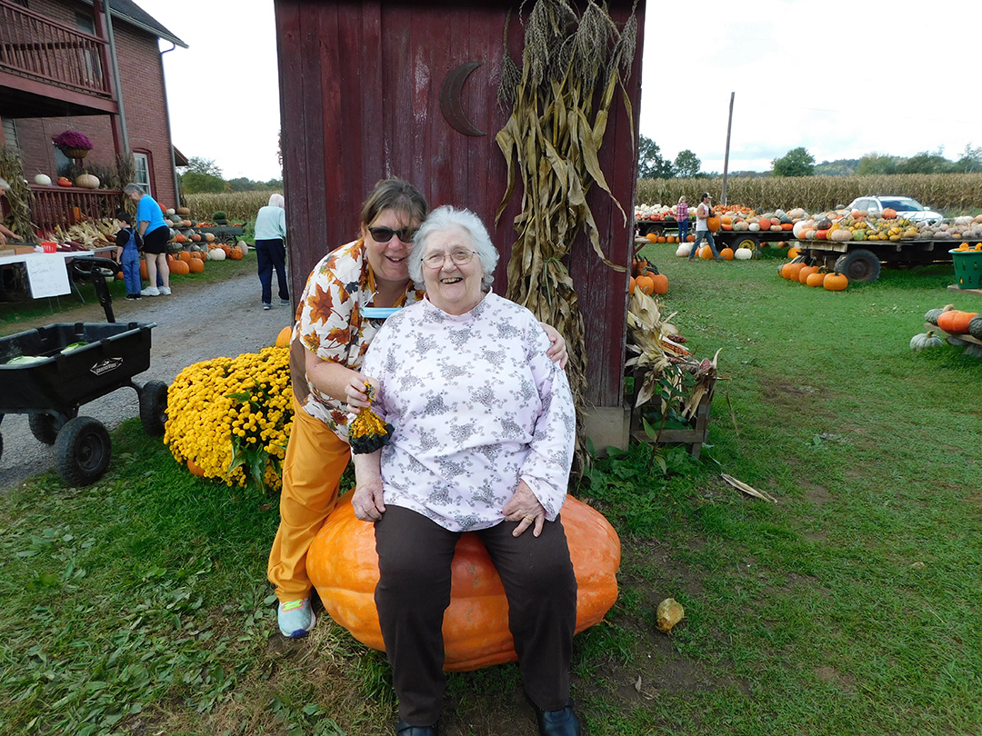 Two women enjoying time outdoors at a pumpkin patch.
