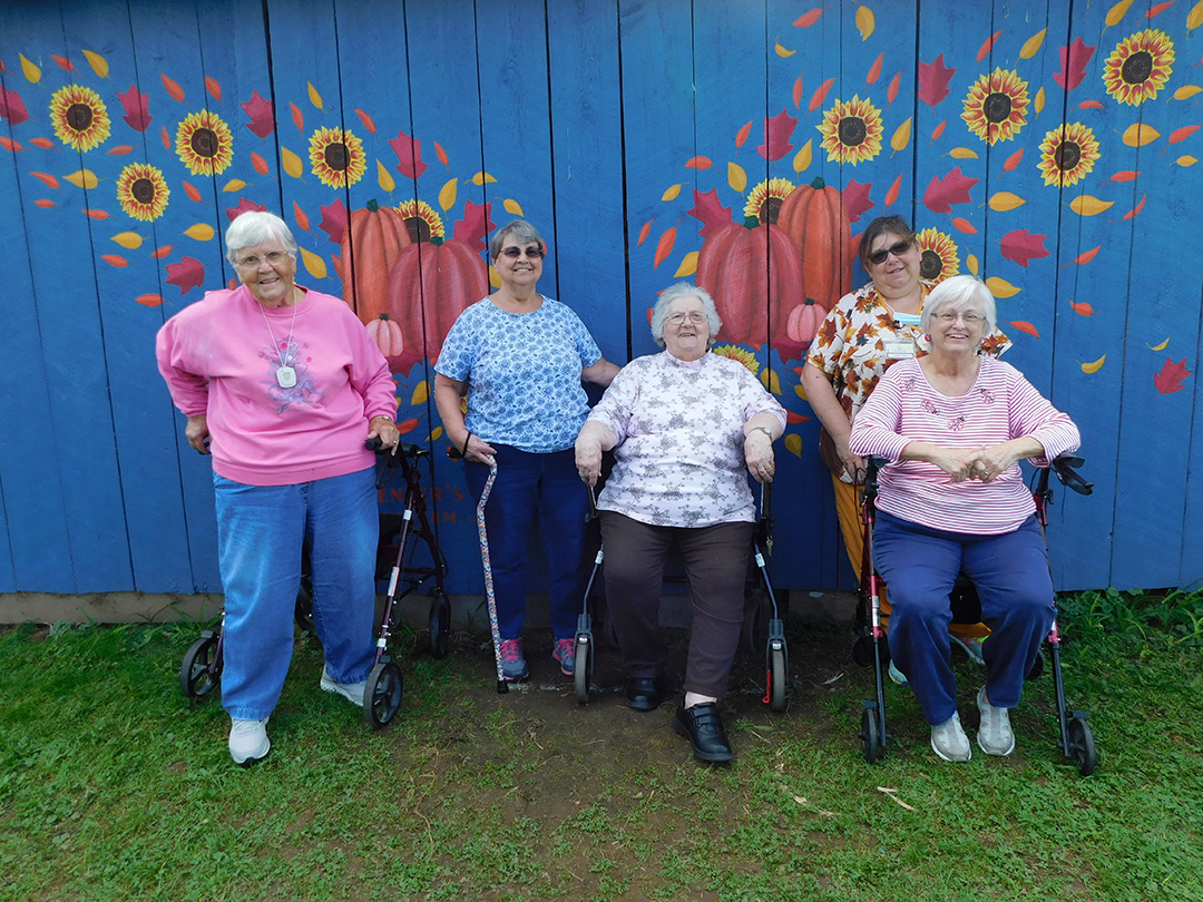 Residents posed in front of a colorful mural