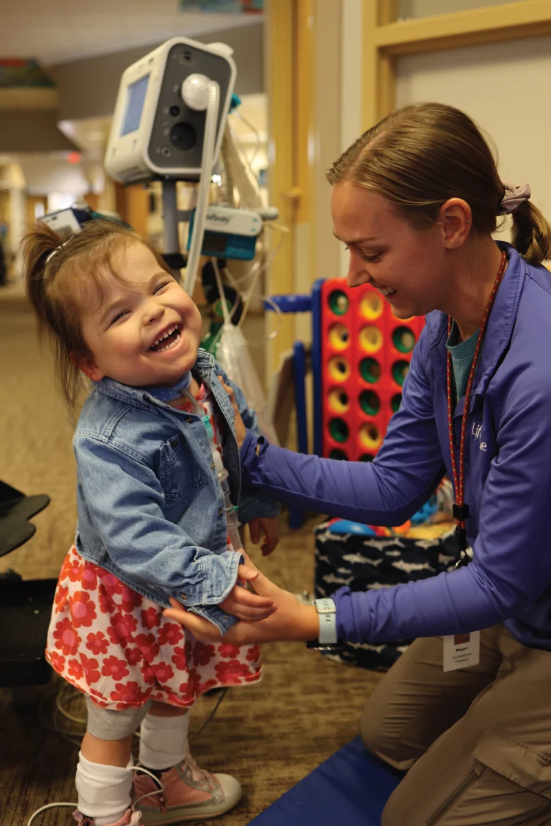 Caregiver assisting a smiling child in a facility