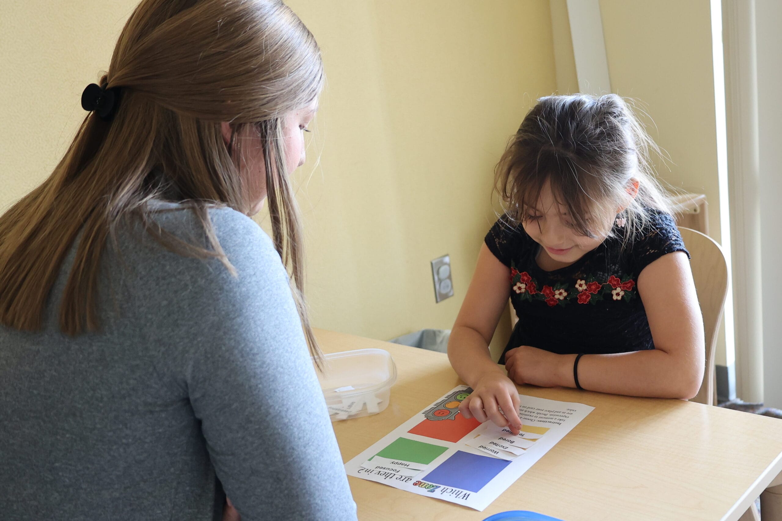 A staff member engaging with a child at a table.