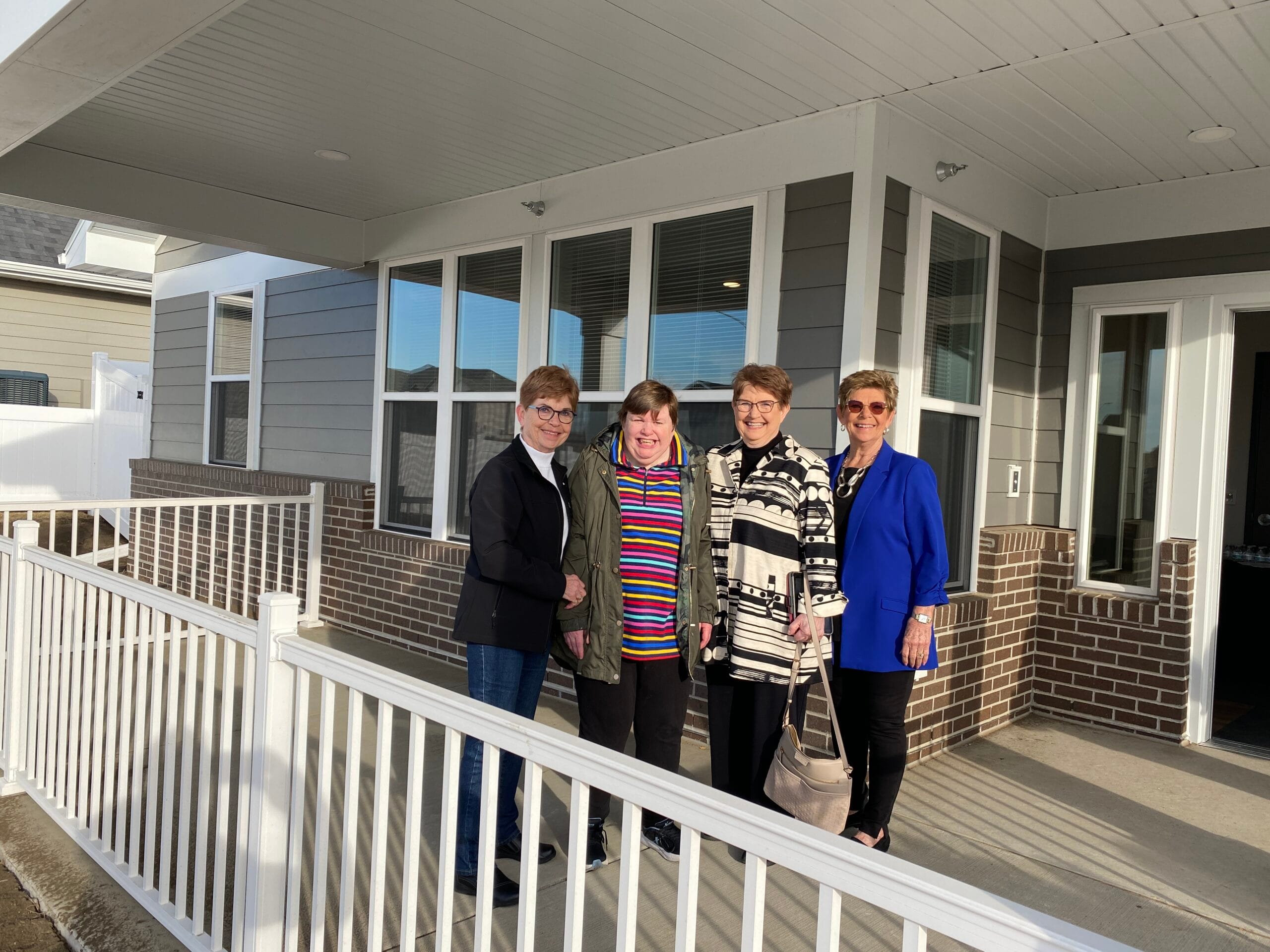 Four women smiling on an outdoor porch